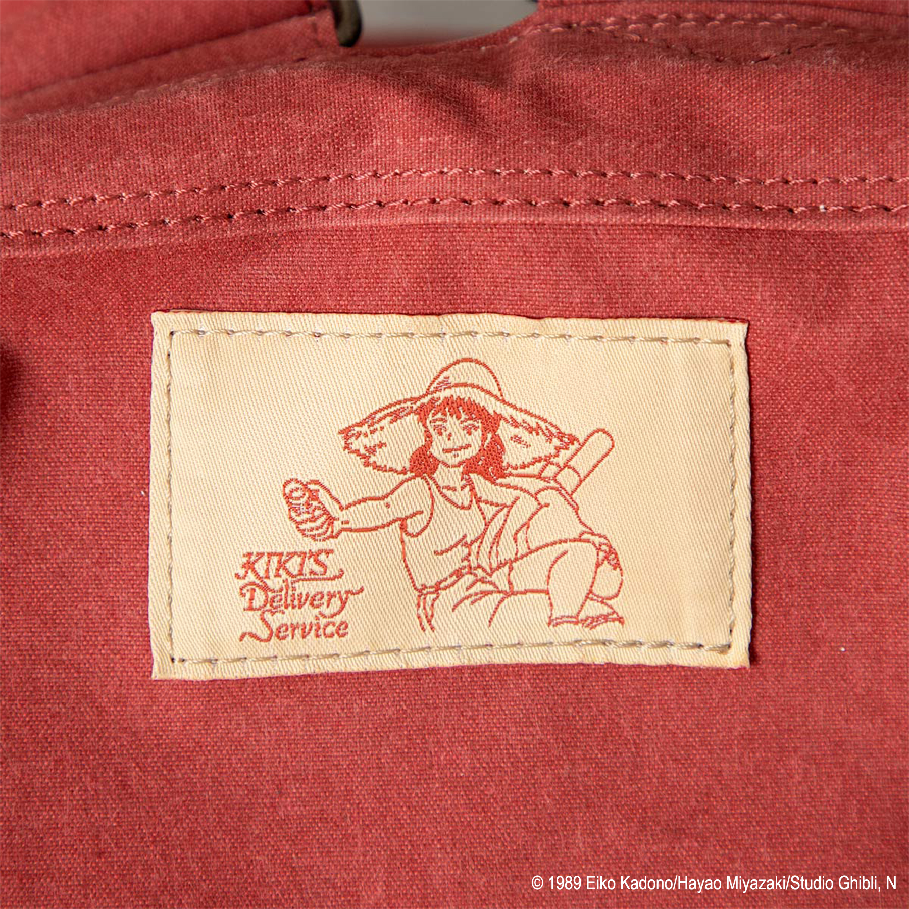 リュック背面織りネーム（タグ） ウルスラがガムをわたす姿　ジブリ「魔女の宅急便」ウルスラのリュック発売！ GBL＆どんぐり共和国 2026年3月20日（金）